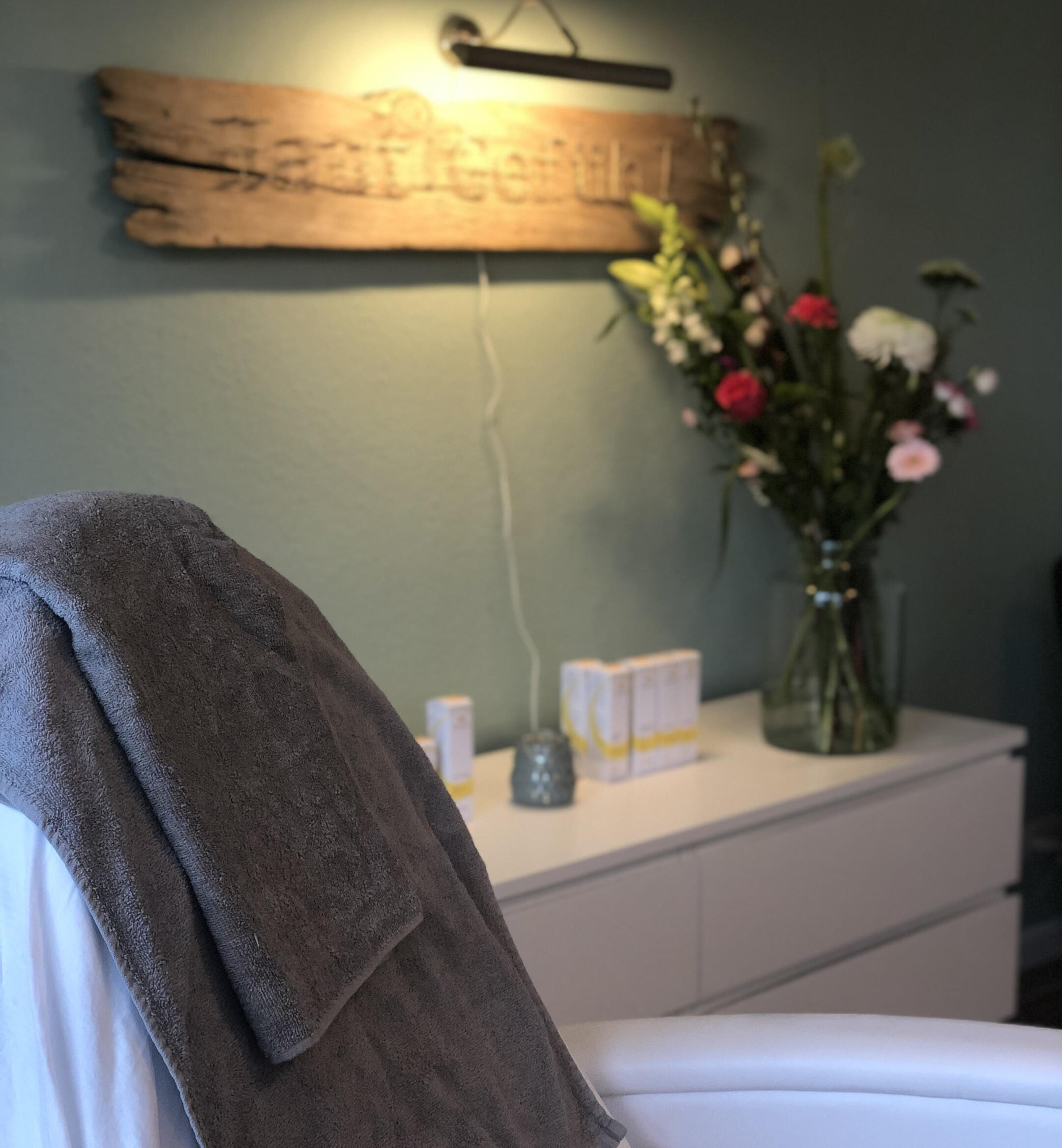 Kosmetik Behandlungsstuhl mit Handtuch über der Rückenlehne mit Blumen im Hintergrund